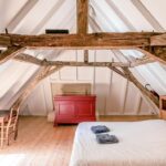 double bed in a bedroom with chair and chest of drawers