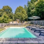 fenced pool with long chairs and umbrella